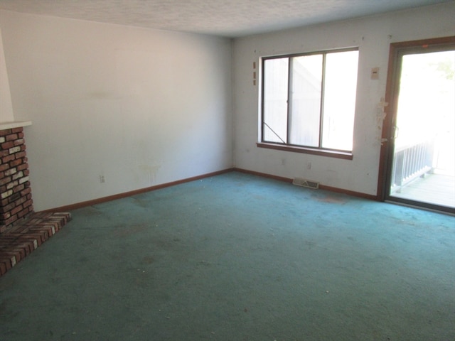 unfurnished living room featuring carpet flooring, a textured ceiling, and a healthy amount of sunlight