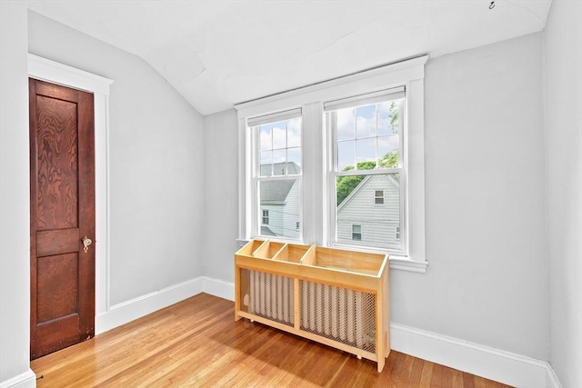 unfurnished room featuring vaulted ceiling, light wood-style flooring, and baseboards