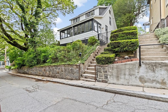 view of front of home featuring stairs and a sunroom