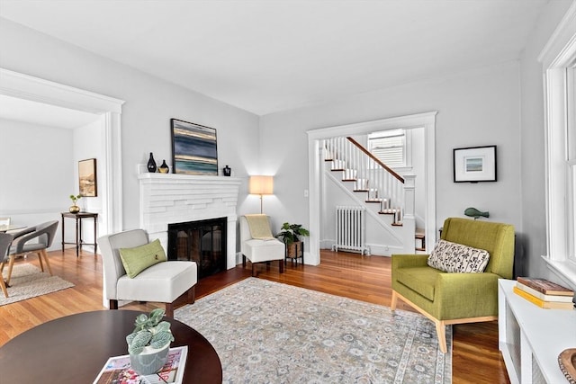 living room with radiator, stairway, and wood finished floors