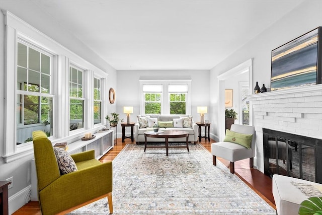 living area with a brick fireplace, wood finished floors, and baseboards