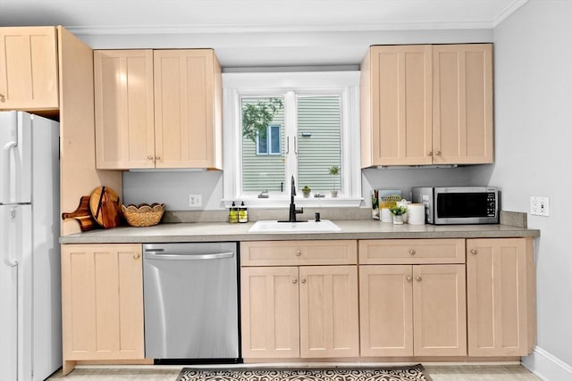kitchen with appliances with stainless steel finishes, a sink, light brown cabinets, light countertops, and ornamental molding