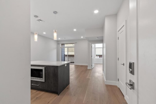 kitchen featuring visible vents, light countertops, light wood-style floors, and stainless steel microwave