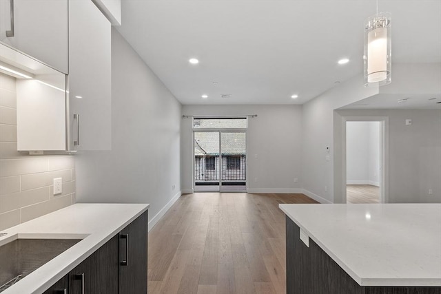 kitchen featuring light countertops, decorative light fixtures, light wood finished floors, and decorative backsplash