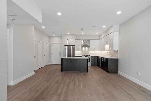 kitchen featuring white cabinetry, tasteful backsplash, a center island, stainless steel appliances, and wall chimney range hood