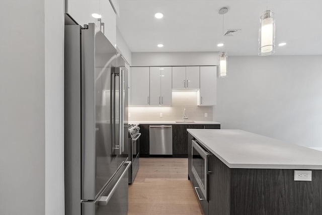 kitchen with light countertops, stainless steel appliances, a sink, visible vents, and white cabinets