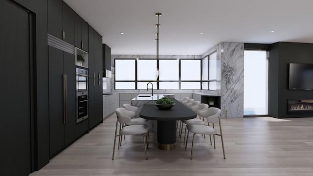 dining room with floor to ceiling windows, sink, and light wood-type flooring