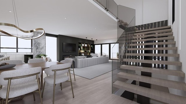 living room with a towering ceiling, plenty of natural light, light hardwood / wood-style floors, and a wall of windows