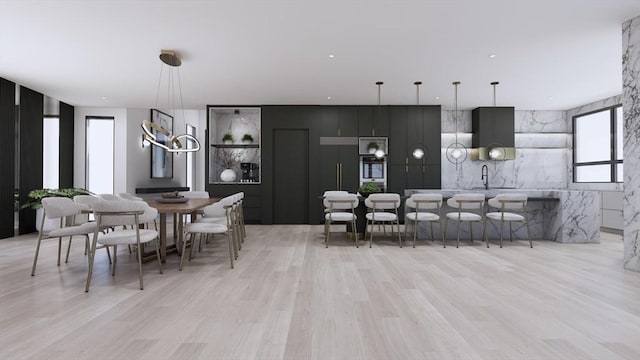 kitchen featuring decorative light fixtures, sink, kitchen peninsula, and light hardwood / wood-style flooring