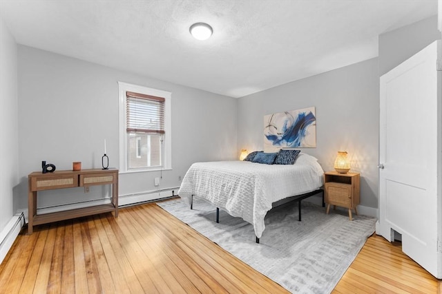 253 Sycamore St Unit 1, Watertown, MA 02472 - bedroom featuring light wood-style floors, a baseboard radiator, a baseboard heating unit, and baseboards