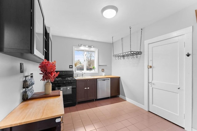 253 Sycamore St Unit 1, Watertown, MA 02472 - kitchen with black gas range oven, stainless steel dishwasher, a sink, wooden counters, and light tile patterned floors