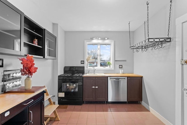 253 Sycamore St Unit 1, Watertown, MA 02472 - kitchen featuring dishwasher, black gas range oven, a sink, light tile patterned floors, and baseboards