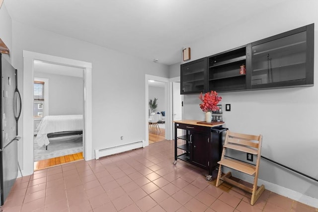 253 Sycamore St Unit 1, Watertown, MA 02472 - kitchen with a baseboard radiator, dark cabinetry, freestanding refrigerator, baseboards, and tile patterned flooring
