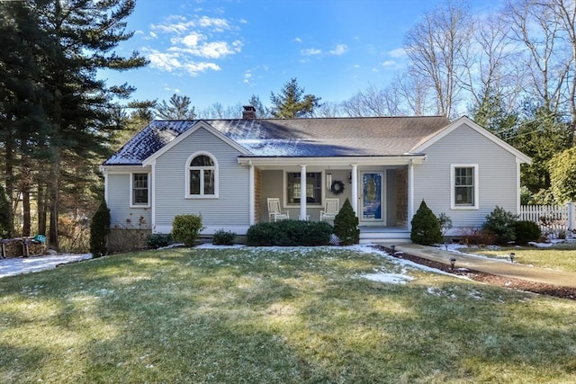 ranch-style home featuring a chimney, roof with shingles, a porch, and a front lawn