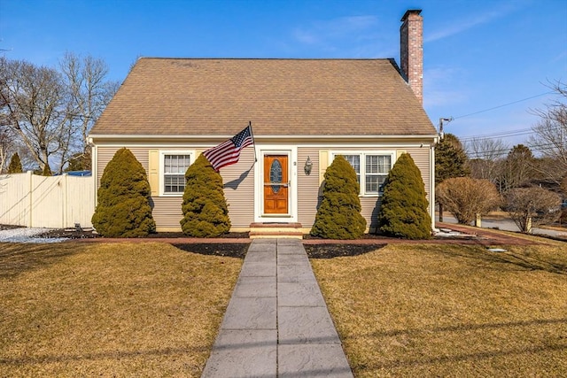 cape cod house featuring a shingled roof, a chimney, fence, and a front lawn