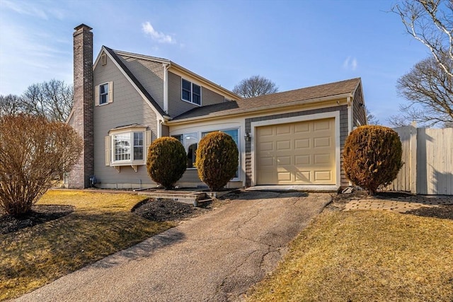 view of front of house featuring a front lawn, aphalt driveway, a chimney, an attached garage, and fence