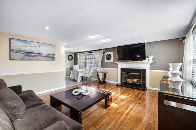 living room with recessed lighting, wood finished floors, a high end fireplace, baseboards, and a textured ceiling