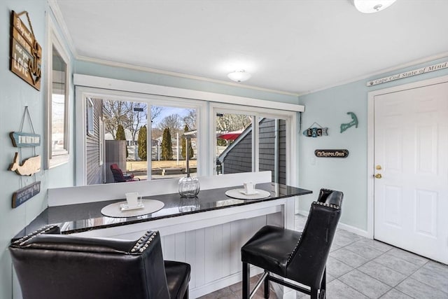 tiled dining space with crown molding and baseboards