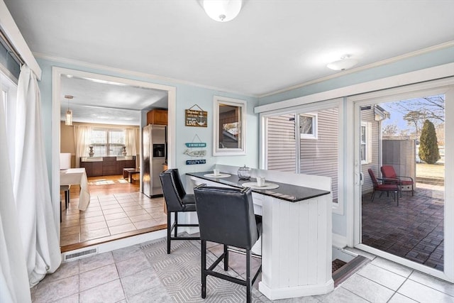 dining area featuring light tile patterned floors, visible vents, and ornamental molding