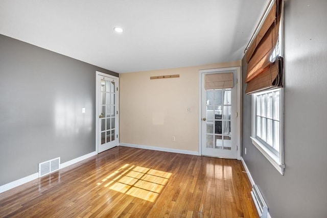 empty room with visible vents, baseboard heating, baseboards, recessed lighting, and wood finished floors