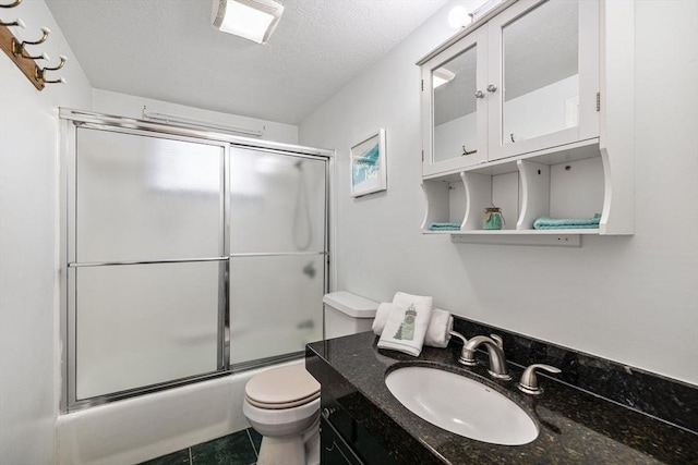 bathroom with tile patterned flooring, shower / bath combination with glass door, toilet, vanity, and a textured ceiling