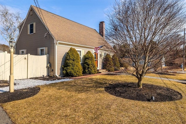 view of home's exterior featuring a chimney, fence, a shingled roof, and a yard