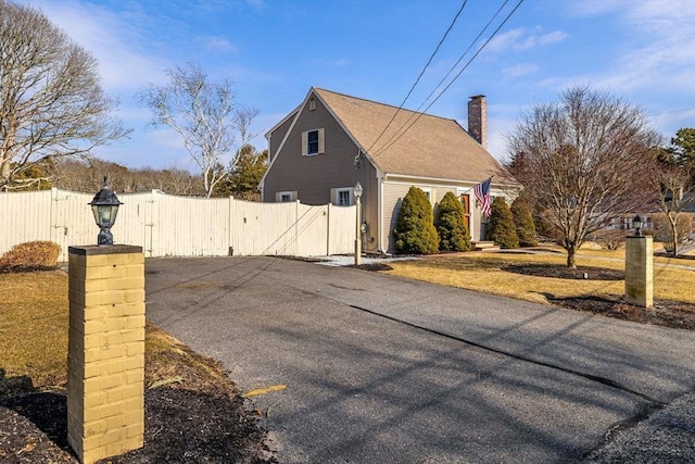 view of side of home with fence, a gate, and a chimney