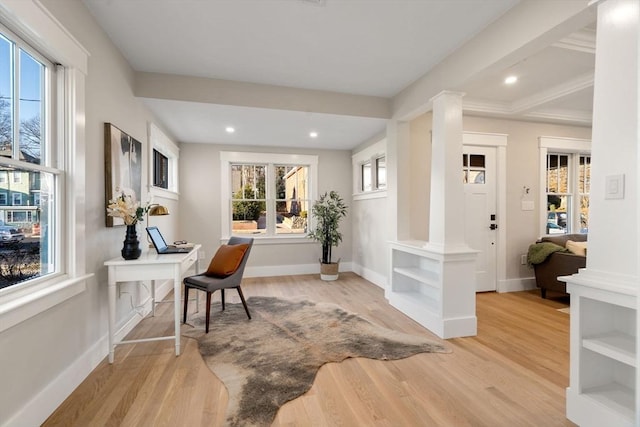 interior space with light hardwood / wood-style floors, ornate columns, and a healthy amount of sunlight