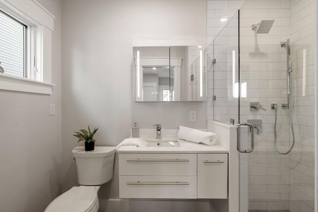 bathroom featuring vanity, a shower with shower door, and toilet