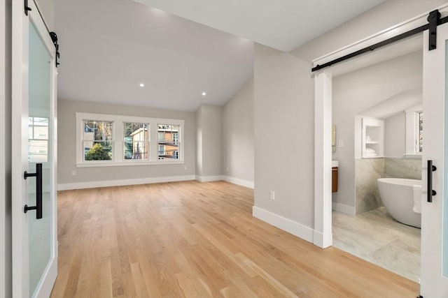 unfurnished living room with a barn door and light wood-type flooring