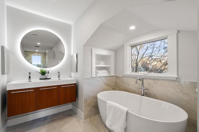 bathroom with a washtub, lofted ceiling, tile walls, and vanity