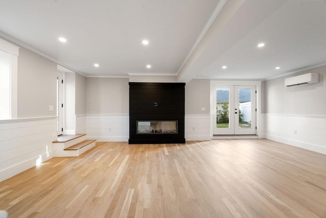 unfurnished living room with french doors, a multi sided fireplace, an AC wall unit, light wood-type flooring, and ornamental molding