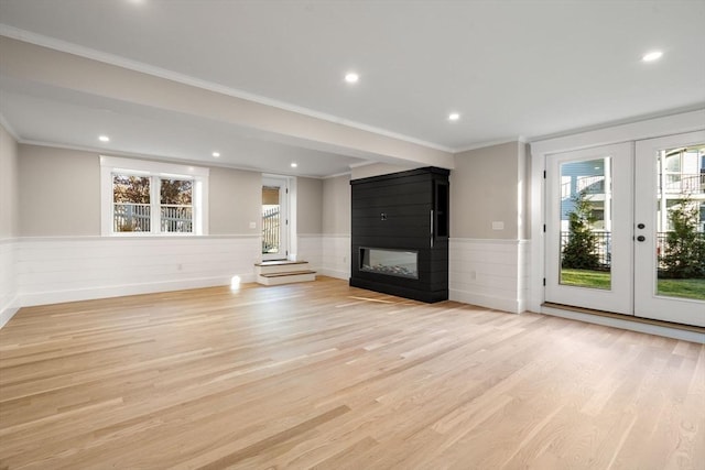 unfurnished living room featuring a multi sided fireplace, french doors, light hardwood / wood-style floors, and ornamental molding