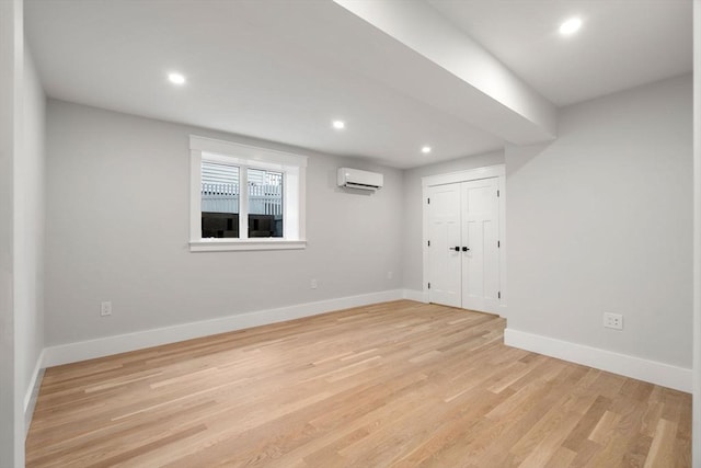 spare room with light hardwood / wood-style floors and an AC wall unit