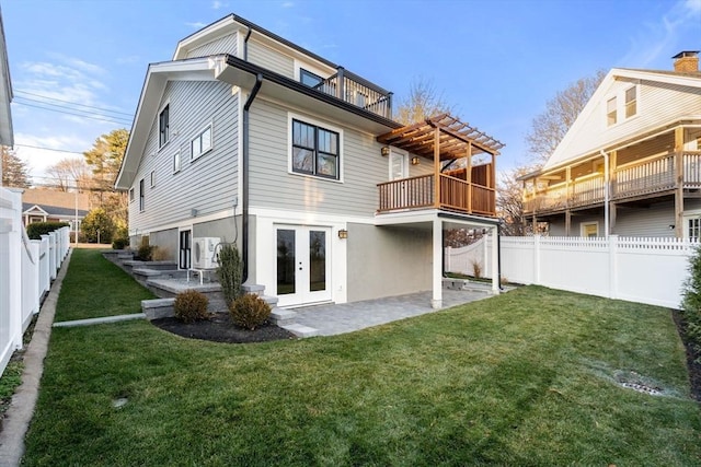 rear view of property with ac unit, french doors, a balcony, and a lawn