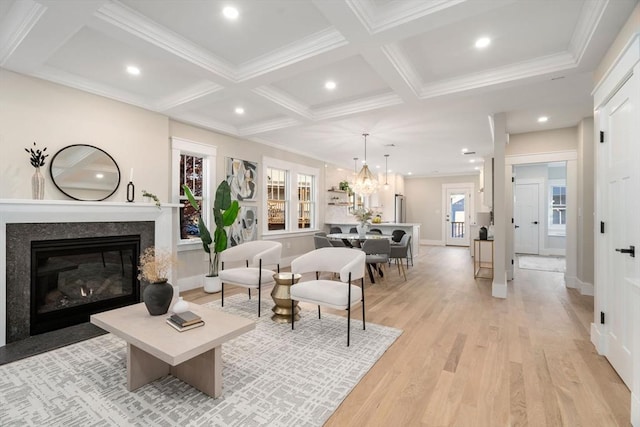 living room featuring a high end fireplace, coffered ceiling, light hardwood / wood-style flooring, ornamental molding, and beamed ceiling