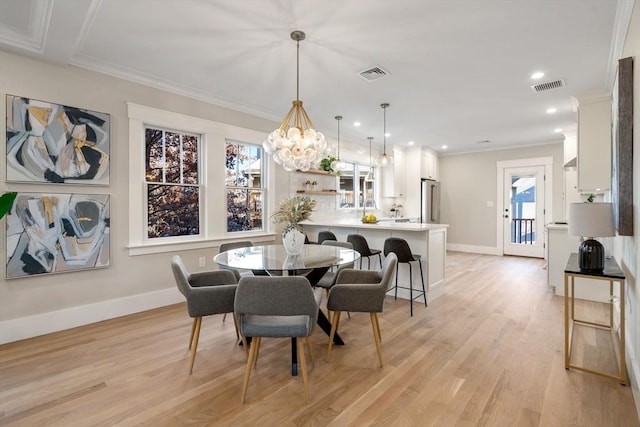 dining area featuring a chandelier, light hardwood / wood-style flooring, and crown molding