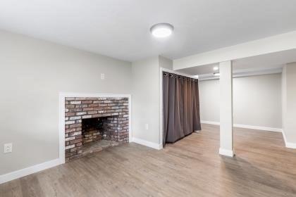 537 S River St, Marshfield, MA 02050 - unfurnished living room with wood finished floors, a brick fireplace, and baseboards