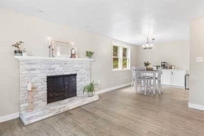 537 S River St, Marshfield, MA 02050 - living room with baseboards, a chandelier, a brick fireplace, and wood finished floors