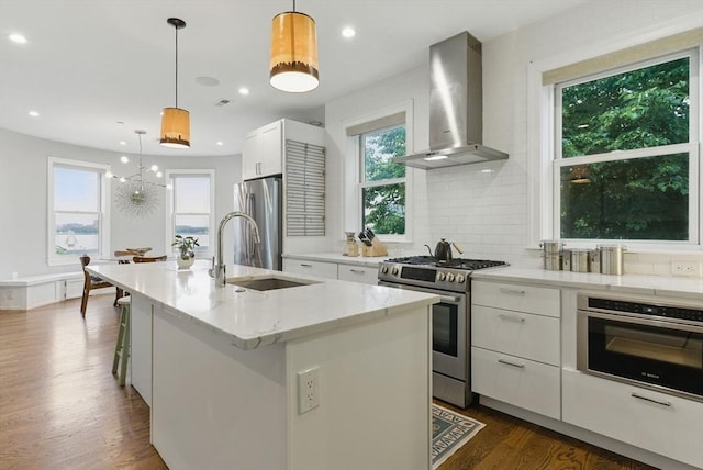 1650 Columbia Rd Unit 3, Boston, MA 02127 - kitchen featuring wall chimney exhaust hood, appliances with stainless steel finishes, white cabinetry, dark wood finished floors, and an island with sink