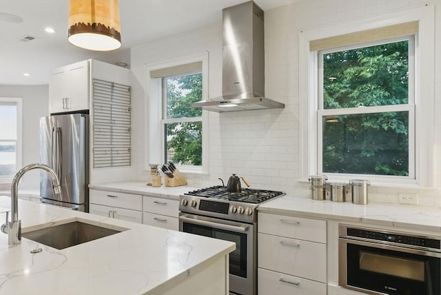 1650 Columbia Rd Unit 3, Boston, MA 02127 - kitchen with appliances with stainless steel finishes, wall chimney range hood, white cabinetry, light stone countertops, and decorative backsplash