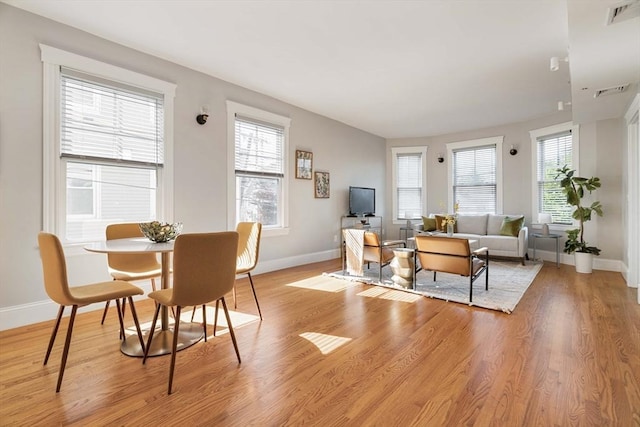 living room with healthy amount of natural light, baseboards, and light wood finished floors