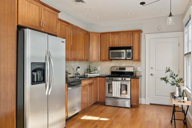 kitchen with stainless steel appliances, a sink, dark countertops, backsplash, and recessed lighting