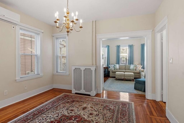 dining space featuring a chandelier, an AC wall unit, wood finished floors, and baseboards