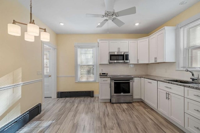 kitchen with a healthy amount of sunlight, appliances with stainless steel finishes, white cabinets, and a sink