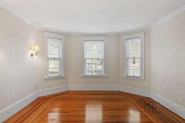 unfurnished room featuring crown molding, baseboards, and wood finished floors