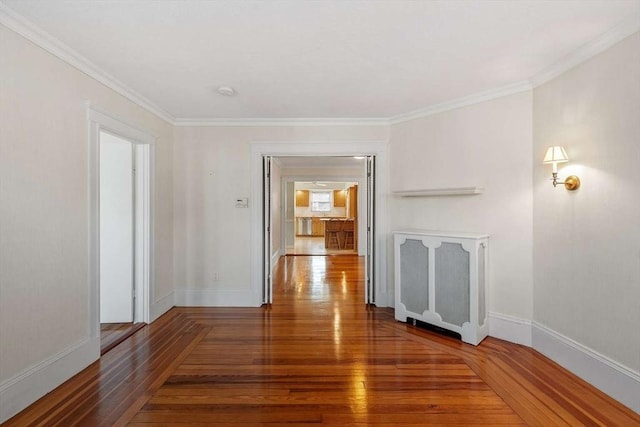 interior space with ornamental molding, hardwood / wood-style flooring, and baseboards