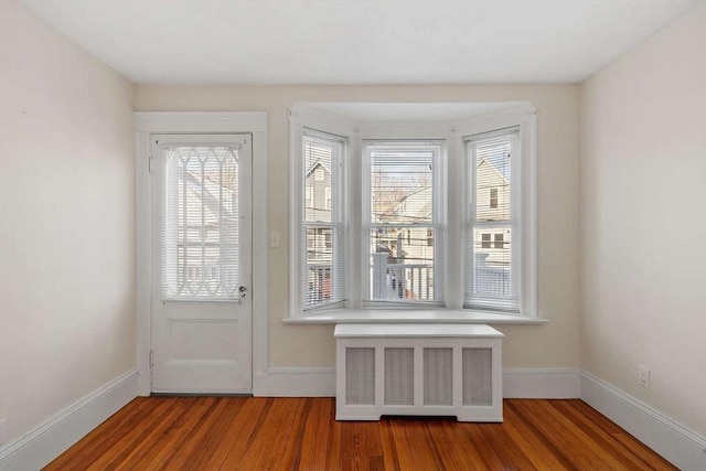 doorway to outside with radiator, baseboards, and wood finished floors