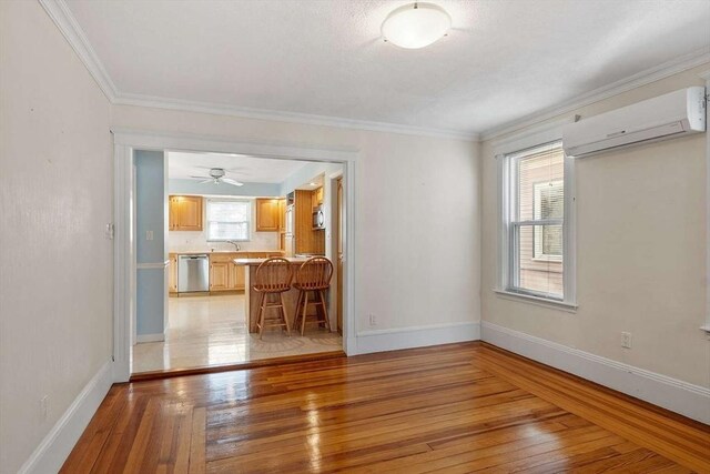 interior space featuring a wall unit AC, light wood finished floors, and baseboards