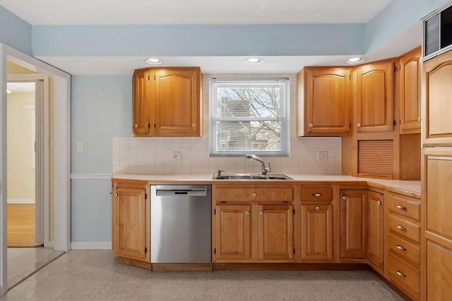 kitchen featuring light countertops, stainless steel dishwasher, a sink, and baseboards